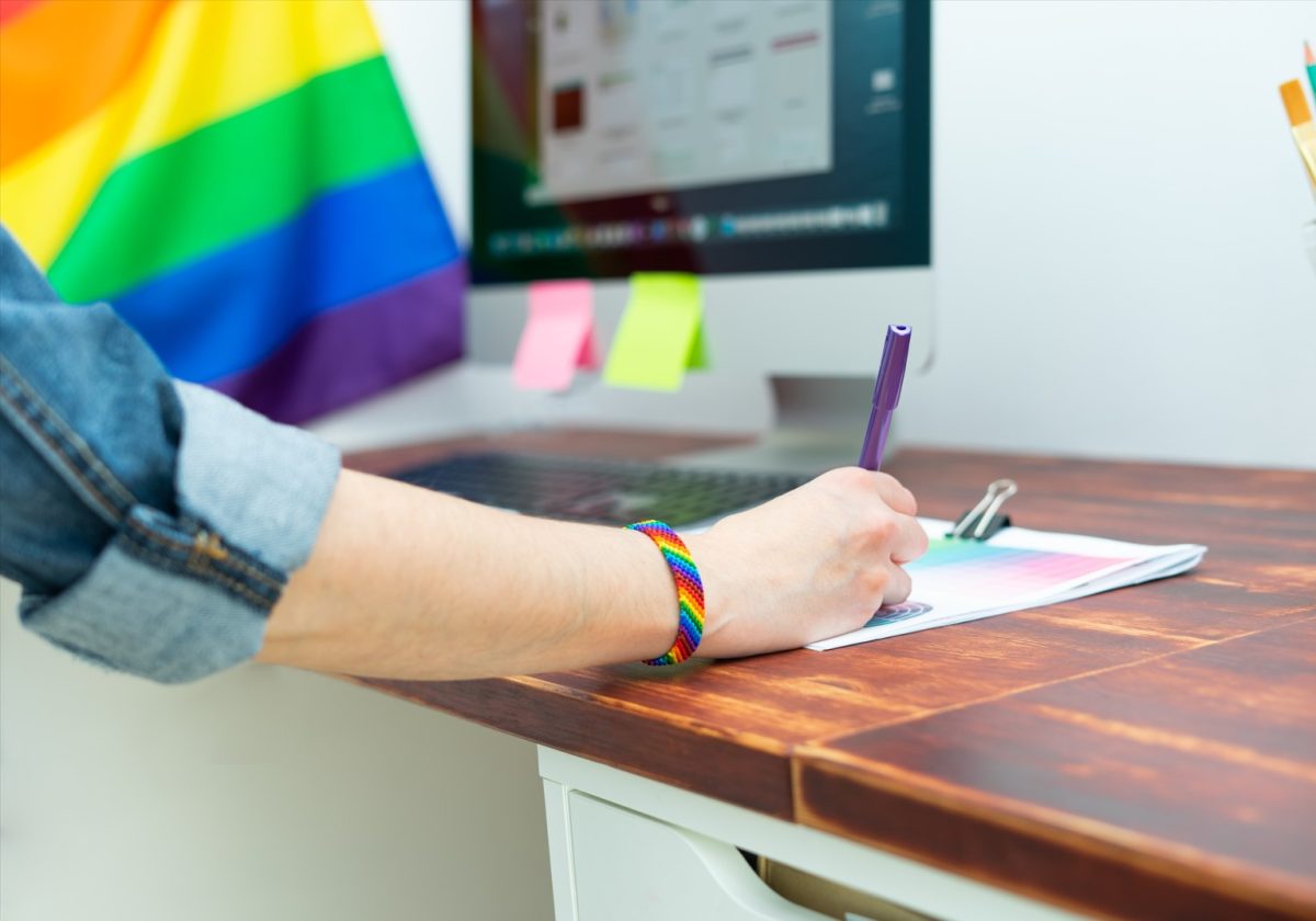 Woman's hand working in office with LGBT decoration and accessories. LGBTQIA culture