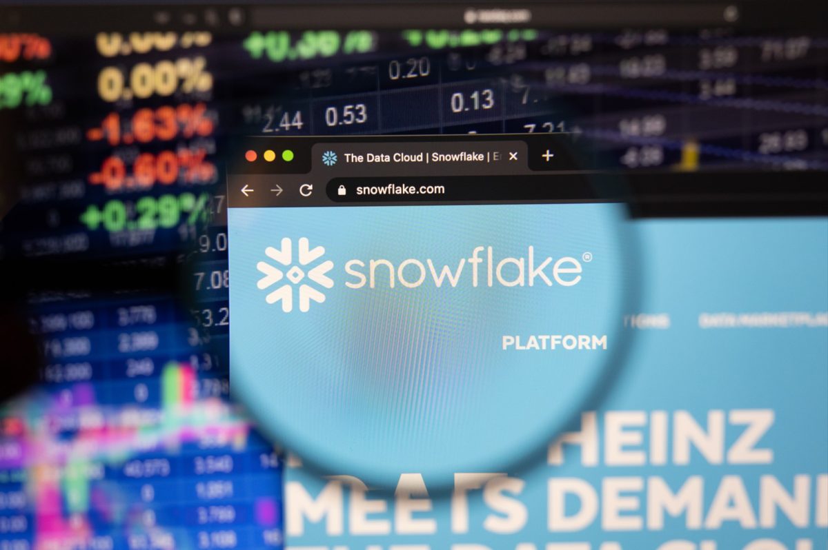 Snowflake company logo on a website with blurry stock market developments in the background,